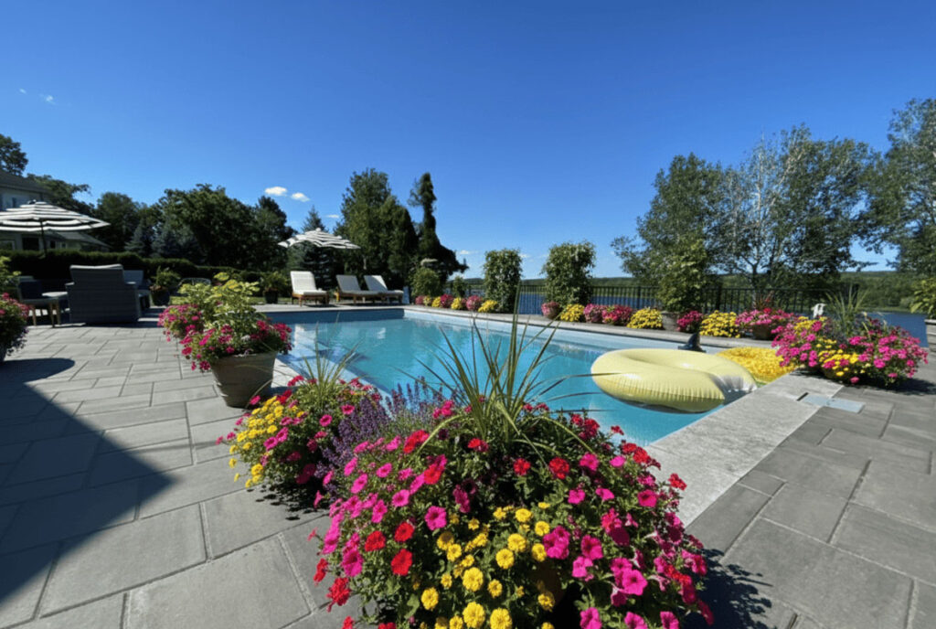 Expert fiberglass pool installation Fredericton NB showcasing a massive stone surround and floral borders