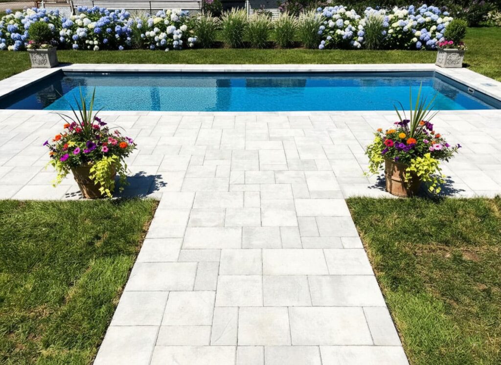 Professional pool installation Fredericton NB showcasing a symmetrical stone walkway and designer floral borders.