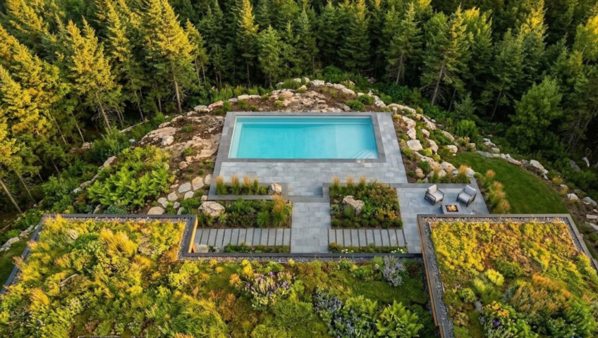 Aerial drone shot of a Fredericton property featuring a vibrant Living Architecture green roof and a premium fiberglass pool engineered into the rocky New Brunswick landscape.